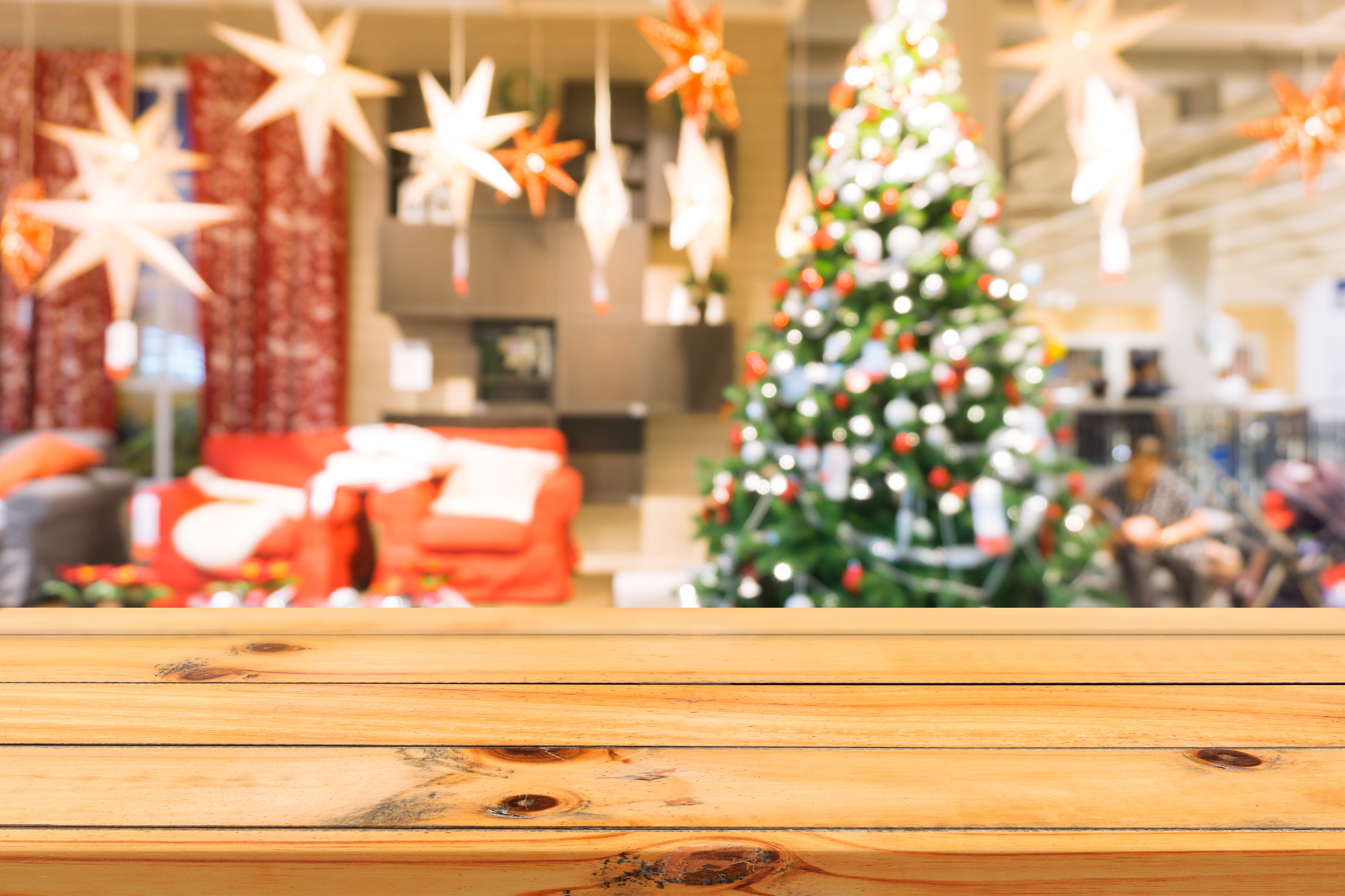 Wooden board empty table top on of blurred background. Perspective brown wood table over blur christmas tree and fireplace background, can be used mock up for montage products display or design layout