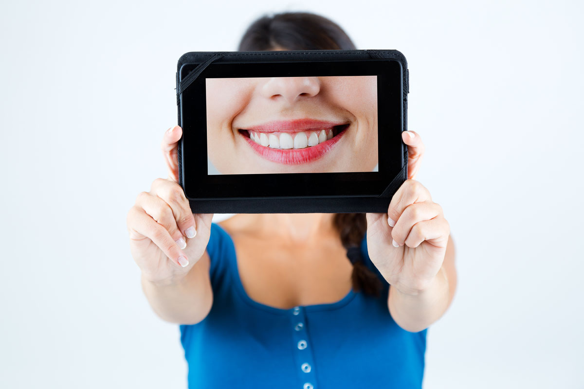 Portrait of beautiful girl holding a picture of a mouth smiling.