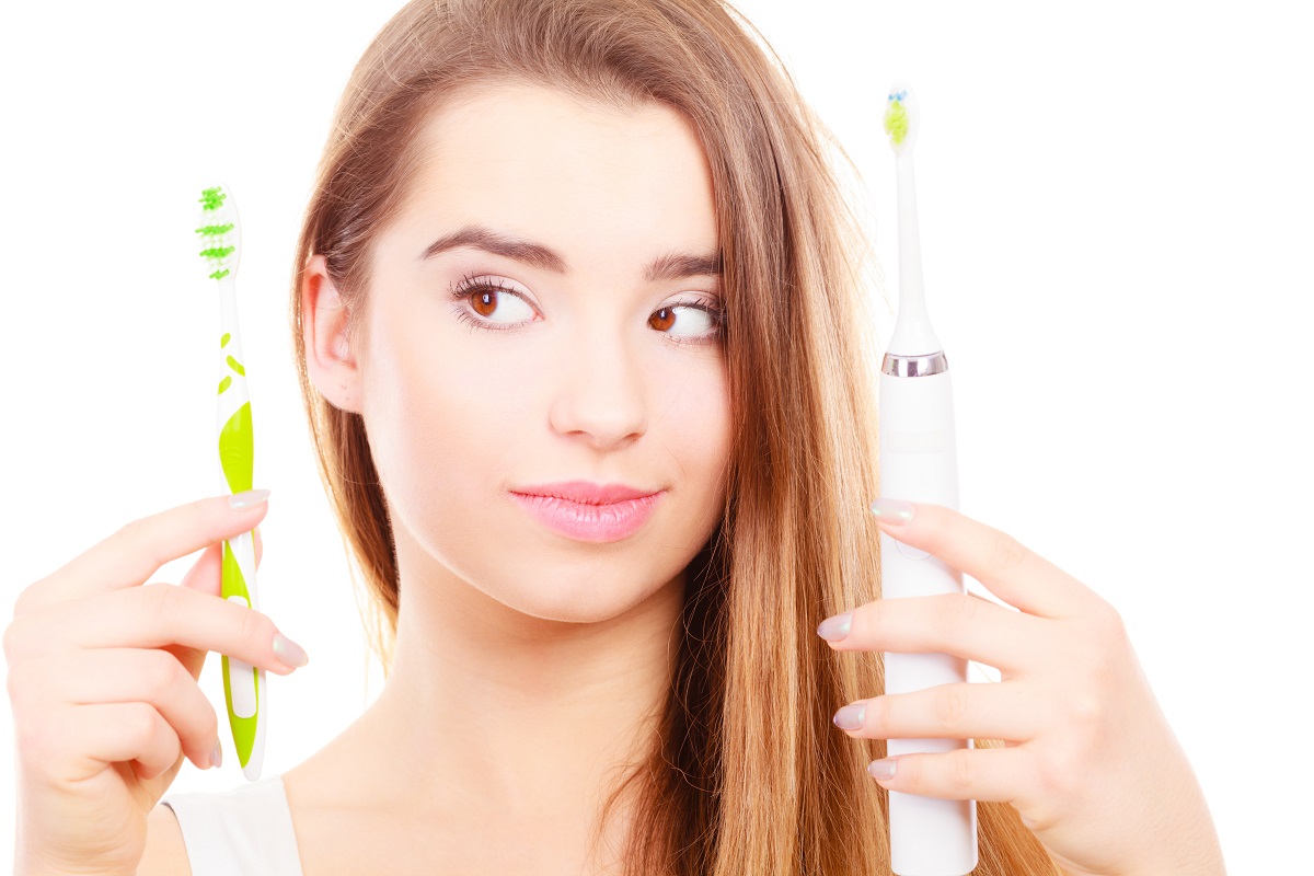 Woman holding, choosing between electric and traditional toothbrush, have to make decision what is best for teeth.