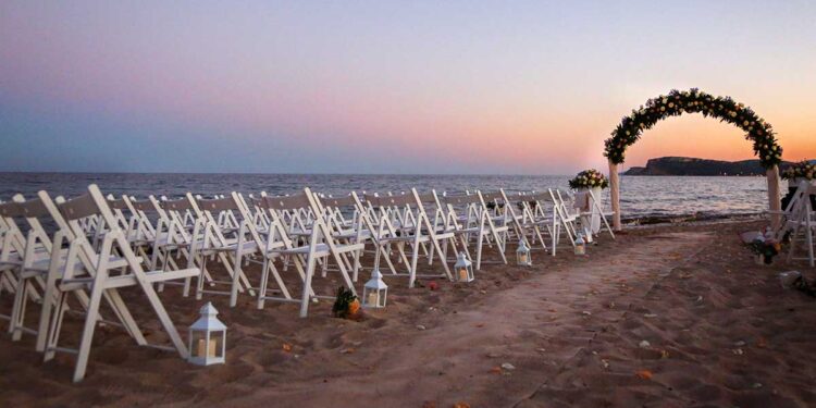 Allestimento di un matrimonio in riva al mare al tramonto. ? AdobeStock | alex.pin