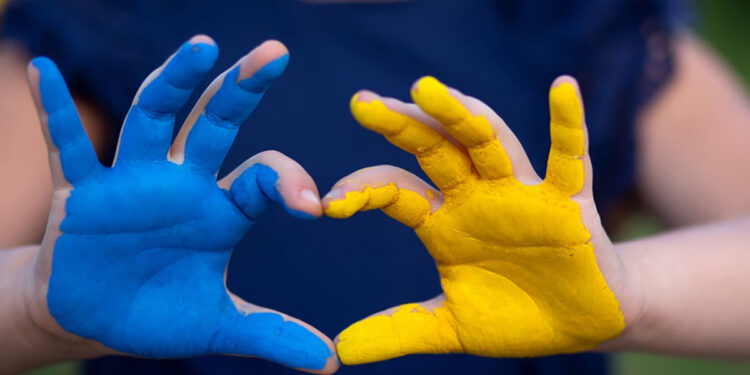 Un bambino con le mani colorate con i colori dell'Ucraina