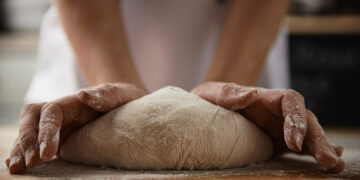 Mani che impastano il pane. 📷 Depositphotos