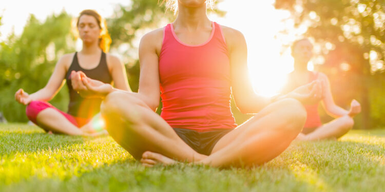 Donne che fanno yoga nel parco. ? Depositphotos