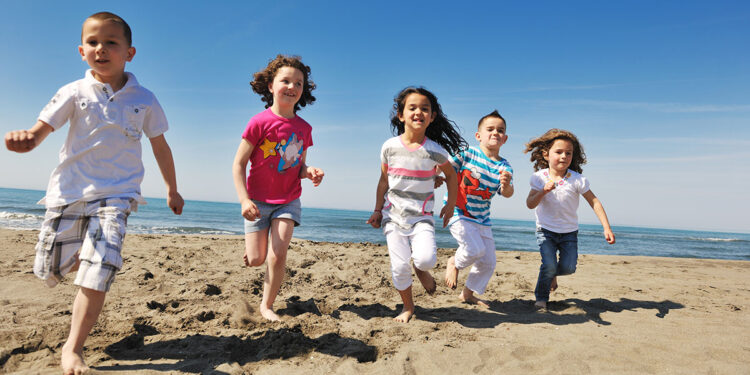 Bambini giocano sulla spiaggia. 📷 Depositphotos