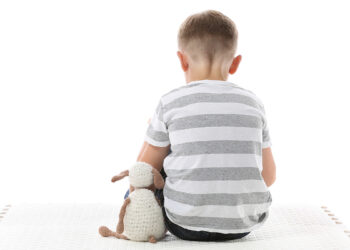 Bambino seduto di spalle, autismo. ? Depositphotos