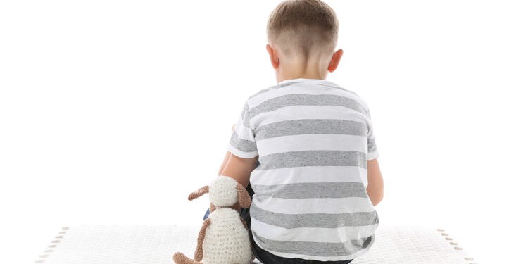 Bambino seduto di spalle, autismo. ? Depositphotos
