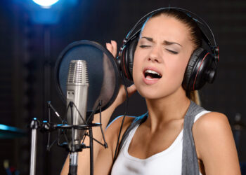 Ragazza che registra canzone in studio. ? Depositphotos